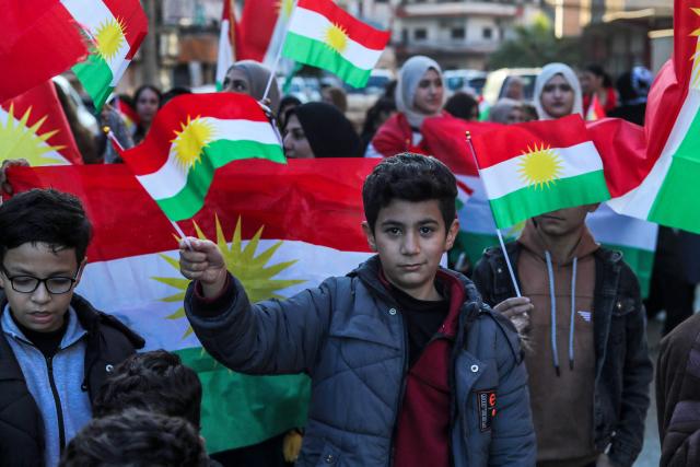 Syrian Kurdish children wave national flags as they celebrate Kurdish Flag Day in the city of Qamishli in northeastern Syria on December 17, 2025. (Photo by Delil SOULEIMAN / AFP)
