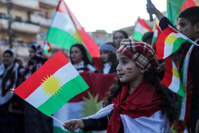 Syrian Kurdish children wave national flags as they celebrate Kurdish Flag Day in the city of Qamishli in northeastern Syria on December 17, 2025. (Photo by Delil SOULEIMAN / AFP)