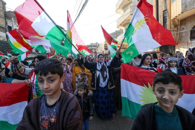 Syrian Kurds wave national flags as they celebrate Kurdish Flag Day in the city of Qamishli in northeastern Syria on December 17, 2025. (Photo by Delil SOULEIMAN / AFP)