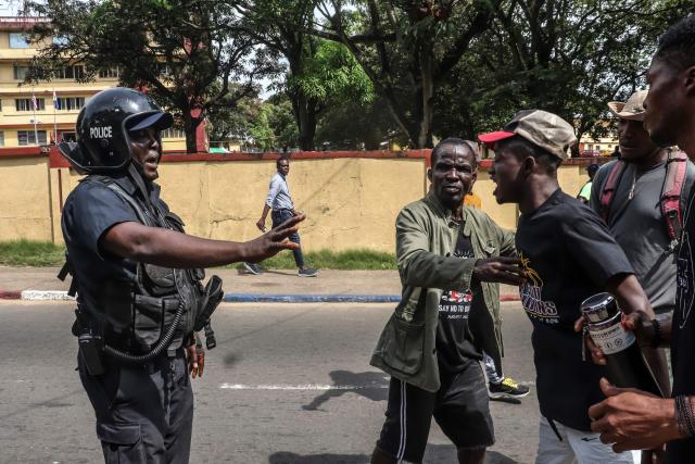 A Liberian police officer gestures as he speaks with protesters  during the “Lead or Leave” demonstration organised by STAND (Solidarity and Trust for a New Day), aimed at pressuring the administration of Liberia's President Joseph Boakai to address corruption, economic hardship and human rights concerns, in Monrovia, on December 17, 2025. (Photo by MATTHEW JACOBS / AFP)