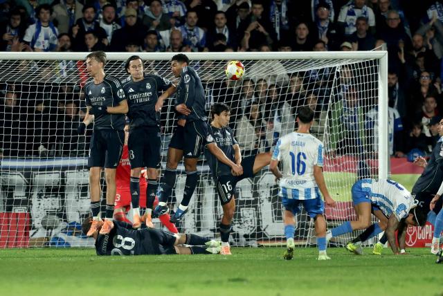 Talavera's Spanish midfielder #16 Isaiah Jeronimo challenges Real Madrid's Ukrainian goalkeeper #13 Andriy Lunin during the Spanish Copa del Rey (King's Cup) round of 32 second leg football match between Talavera CF and Real Madrid CF at El Prado Municipal Stadium in Talavera de la Reina on December 17, 2025. (Photo by Thomas COEX / AFP)