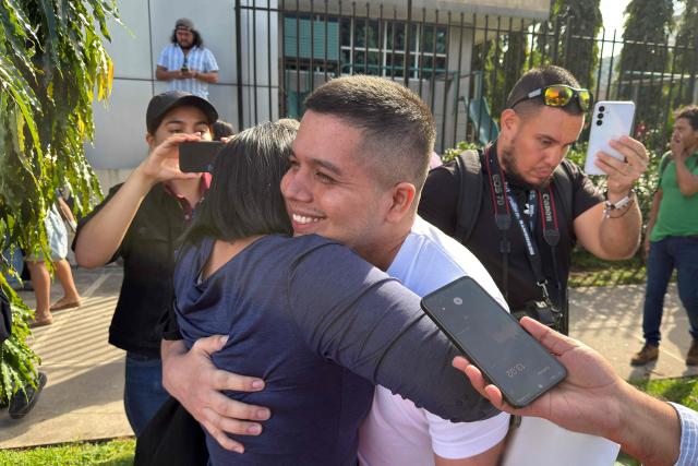 Salvadorian environmental lawyer Alejandro Henriquez hugs a woman after a hearing at the Integrated Judicial Center of Santa Tecla, El Salvador on December 17, 2025. El Salvador's judiciary sentenced Salvadorian environmental lawyer Alejandro Henriquez and local leader Jose Angel Perez to three years in prison for "aggressive resistance" and "public disorder", but granted them conditional release, according to the ruling issued on December 17, 2025. They were arrested last May for protesting near the home of President Nayib Bukele. (Photo by Rudy QUIROZ / AFP)