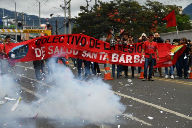 Supporters of the ruling Libertad y Refundacion (LIBRE) party set off firecrackers in front of the Presidential House during a protest in support of Honduran President Xiomara Castro and against electoral fraud in Tegucigalpa on December 17, 2025. (Photo by Orlando SIERRA / AFP)