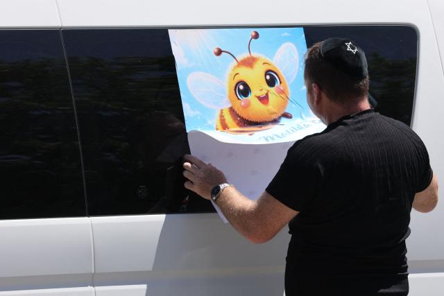 A mourner puts up a poster of a bee on a van outside the location of the funeral of 10-year-old Matilda, who was killed in the December 14 Bondi Beach shooting attack, in Sydney on December 18, 2025. The attack at Bondi Beach on December 14 was one of the deadliest in Australian history. (Photo by DAVID GRAY / AFP)