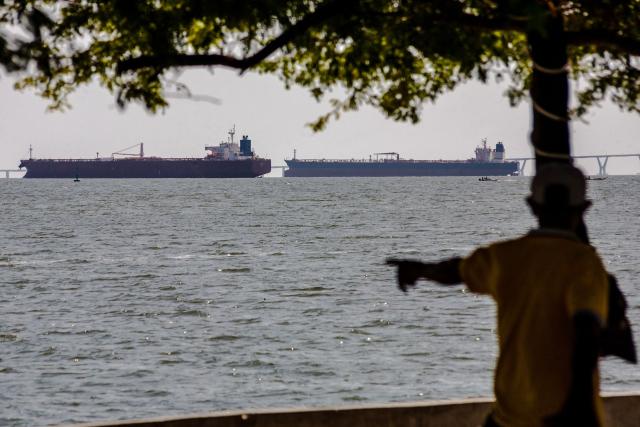 A man watches two crude oil tankers remaining anchored on Lake Maracaibo, near Maracaibo, Zulia state, Venezuela on December 17, 2025. (Photo by Alejandro Paredes / AFP)