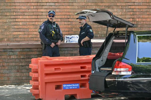 The police is on alert as they stand next to a hearse during the funeral of 10-year-old Matilda, who was killed in the December 14 Bondi Beach shooting attack, in Sydney on December 18, 2025. The attack at Bondi Beach on December 14 was one of the deadliest in Australian history. (Photo by Saeed KHAN / AFP)