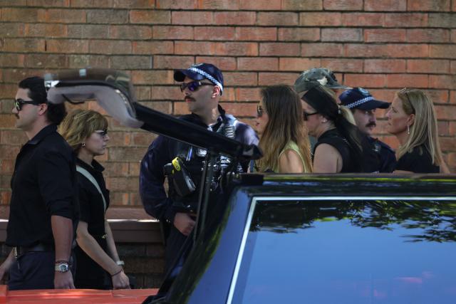 A police officer stands guard as relatives of 10-year-old Matilda, who was killed in the December 14 Bondi Beach shooting attack, walk past before her funeral in Sydney on December 18, 2025. The attack at Bondi Beach on December 14 was one of the deadliest in Australian history. (Photo by DAVID GRAY / AFP)