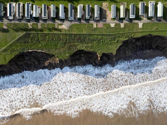 An aerial photograph taken on November 13, 2025 shows a view of the Skirlington Coast holiday park, located on the North sea coast in an area which is experiencing intense coastal erosion, near Hornsea, in the East Riding of Yorkshire, north eastern England. The Holderness coastline, covering 61km between the Spurn nature reserve in the south and Flamborough in the north, experiences one of the fastest rates of erosion in Europe. The Holderness cliffs are eroding at average rate of around 1.5 metres per year, although individual cliff losses can exceed 20 metres per year. Over the last 1000 years, the coast has retreated by around 2 kilometres, resulting in the destruction of 26 villages listed in the Domesday survey of 1086. (Photo by Oli SCARFF / AFP)