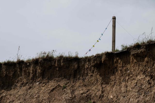 A photograph taken on June 12, 2025 shows a garden washing line at the top of a cliff on the North Sea coast that is undergoing coastal erosion, near the village of Skipsea, near Hornsea, in the East Riding of Yorkshire, north eastern England. The Holderness coastline, covering 61km between the Spurn nature reserve in the south and Flamborough in the north, experiences one of the fastest rates of erosion in Europe. The Holderness cliffs are eroding at average rate of around 1.5 metres per year, although individual cliff losses can exceed 20 metres per year. Over the last 1000 years, the coast has retreated by around 2 kilometres, resulting in the destruction of 26 villages listed in the Domesday survey of 1086. (Photo by OLI SCARFF / AFP)