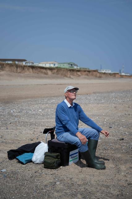 Alan Quinlan watches his rod as he fishes on Easington Beach, on the North Sea coast which is experiencing intense coastal erosion, near the village of Easington, near Withernsea, in the East Riding of Yorkshire, north eastern England, on June 17, 2025. The Holderness coastline, covering 61km between the Spurn nature reserve in the south and Flamborough in the north, experiences one of the fastest rates of erosion in Europe. The Holderness cliffs are eroding at average rate of around 1.5 metres per year, although individual cliff losses can exceed 20 metres per year. Over the last 1000 years, the coast has retreated by around 2 kilometres, resulting in the destruction of 26 villages listed in the Domesday survey of 1086. (Photo by Oli SCARFF / AFP)