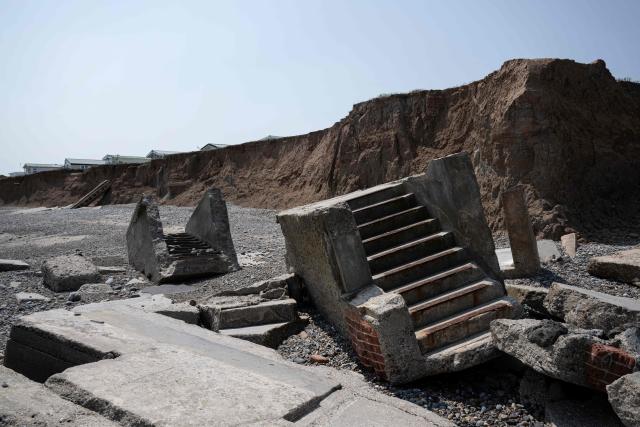 A photograph taken on June 17, 2025 shows the remnants of the Godwin Artillery Battery, initially constructed on the cliff top in 1915, but now located on the beach following intense coastal erosion, near the village of Kilnsea, near Withernsea, in the East Riding of Yorkshire, north eastern England. The Holderness coastline, covering 61km between the Spurn nature reserve in the south and Flamborough in the north, experiences one of the fastest rates of erosion in Europe. The Holderness cliffs are eroding at average rate of around 1.5 metres per year, although individual cliff losses can exceed 20 metres per year. Over the last 1000 years, the coast has retreated by around 2 kilometres, resulting in the destruction of 26 villages listed in the Domesday survey of 1086. (Photo by Oli SCARFF / AFP)