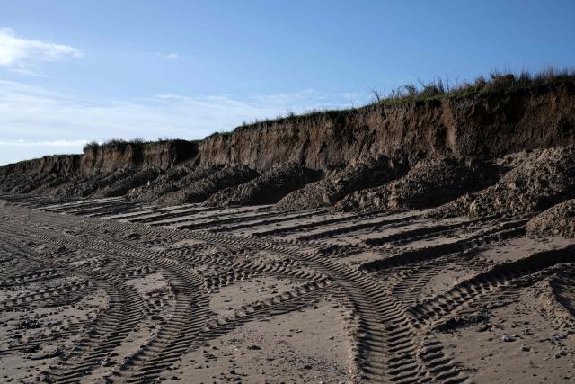 A photograph taken on November 13, 2025 shows earth deposited at the base of cliffs on Fraisthorpe Beach on the North sea coast which are experiencing intense coastal erosion, near Bridlington, in the East Riding of Yorkshire, north eastern England. The Holderness coastline, covering 61km between the Spurn nature reserve in the south and Flamborough in the north, experiences one of the fastest rates of erosion in Europe. The Holderness cliffs are eroding at average rate of around 1.5 metres per year, although individual cliff losses can exceed 20 metres per year. Over the last 1000 years, the coast has retreated by around 2 kilometres, resulting in the destruction of 26 villages listed in the Domesday survey of 1086. (Photo by Oli SCARFF / AFP)