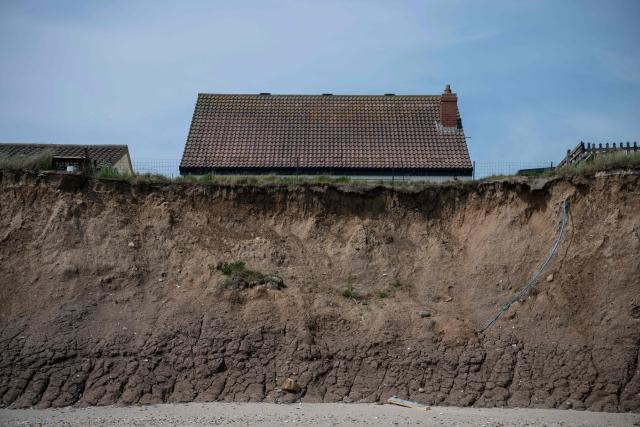 A photograph taken on June 12, 2025 shows a cliff on the North Sea coast that is undergoing coastal erosion, close to properties near the village of Skipsea, near Hornsea, in the East Riding of Yorkshire, north eastern England. The Holderness coastline, covering 61km between the Spurn nature reserve in the south and Flamborough in the north, experiences one of the fastest rates of erosion in Europe. The Holderness cliffs are eroding at average rate of around 1.5 metres per year, although individual cliff losses can exceed 20 metres per year. Over the last 1000 years, the coast has retreated by around 2 kilometres, resulting in the destruction of 26 villages listed in the Domesday survey of 1086. (Photo by OLI SCARFF / AFP)