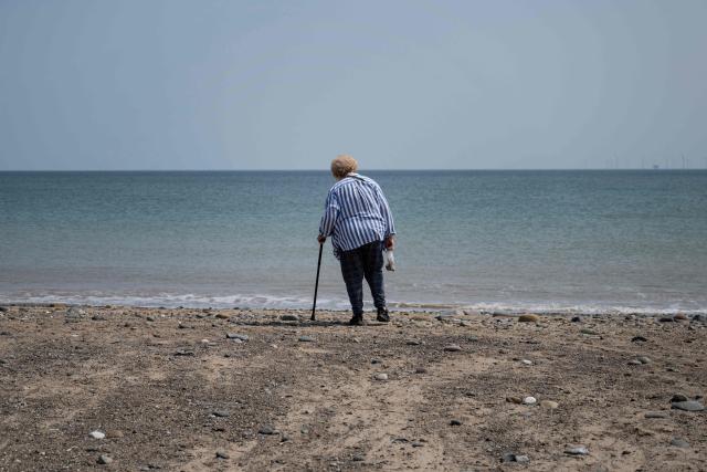 A woman collects stones and seaweed as she beachcombs on Easington Beach, on the North Sea coast which is experiencing intense coastal erosion, near the village of Easington, near Withernsea, in the East Riding of Yorkshire, north eastern England, on June 17, 2025. The Holderness coastline, covering 61km between the Spurn nature reserve in the south and Flamborough in the north, experiences one of the fastest rates of erosion in Europe. The Holderness cliffs are eroding at average rate of around 1.5 metres per year, although individual cliff losses can exceed 20 metres per year. Over the last 1000 years, the coast has retreated by around 2 kilometres, resulting in the destruction of 26 villages listed in the Domesday survey of 1086. (Photo by Oli SCARFF / AFP)
