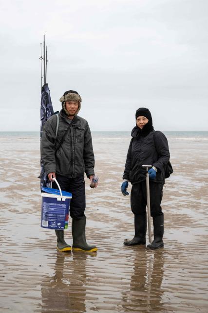 Leong (L) and Fiona search the beach with a falling tide for worms they will then use as fishing bait, along a section of the North Sea coast that is undergoing coastal erosion, near the village of Barmston, near Bridlington, in the East Riding of Yorkshire, north eastern England, on June 17, 2025. The Holderness coastline, covering 61km between the Spurn nature reserve in the south and Flamborough in the north, experiences one of the fastest rates of erosion in Europe. The Holderness cliffs are eroding at average rate of around 1.5 metres per year, although individual cliff losses can exceed 20 metres per year. Over the last 1000 years, the coast has retreated by around 2 kilometres, resulting in the destruction of 26 villages listed in the Domesday survey of 1086. (Photo by Oli SCARFF / AFP)