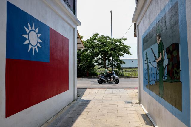 (FILES) A motorist commutes past paintings on a wall of the Taiwan flag and a soldier in Taiwan's Kinmen on May 18, 2024. Donald Trump's administration has given its approval to sell $11 billion of weapons to Taiwan, the second batch of such sales since the US president returned to office, Taipei said on December 18, 2025. (Photo by I-Hwa CHENG / AFP)