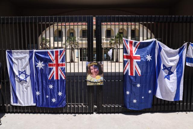 A poster of 10-year-old Matilda, who was killed in the December 14 Bondi Beach shooting attack, is hung next to flags of Australia and Israel on the gate of the Bondi Pavilion, in Sydney on December 18, 2025. The attack at Bondi Beach on December 14 was one of the deadliest in Australian history. (Photo by DAVID GRAY / AFP)