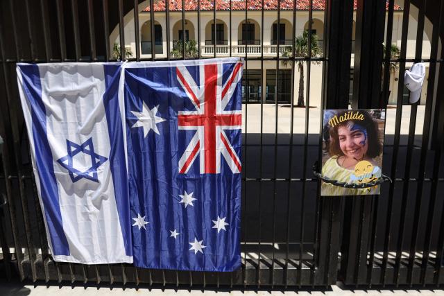 A poster of 10-year-old Matilda, who was killed in the December 14 Bondi Beach shooting attack, is hung next to flags of Australia and Israel on the gate of the Bondi Pavilion, in Sydney on December 18, 2025. The attack at Bondi Beach on December 14 was one of the deadliest in Australian history. (Photo by DAVID GRAY / AFP)