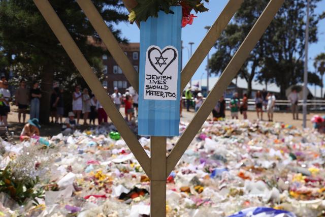 A sign reading "Jewish Lives Should Matter, Too" is seen at the floral tributes area outside Bondi Pavilion in Sydney on December 18, 2025, to honour victims of the Bondi Beach shooting. The attack at Bondi Beach on December 14 was one of the deadliest in Australian history. (Photo by DAVID GRAY / AFP)