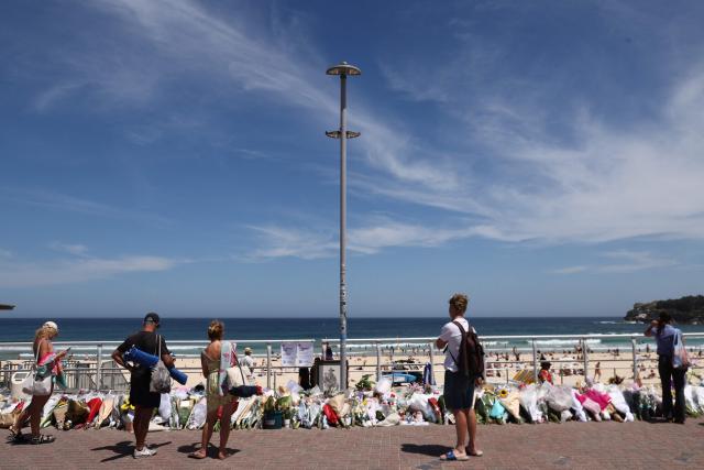 People look at floral tributes left at the promenade of Bondi Beach in Sydney on December 18, 2025, to honour victims of the shooting that took place there on December 14. The attack at Bondi Beach on December 14 was one of the deadliest in Australian history. (Photo by DAVID GRAY / AFP)