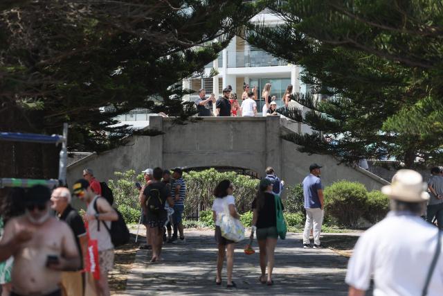 People are seen at the footbridge used by the father-and-son gunmen during the December 14 Bondi Beach shooting, in Sydney on December 18, 2025. The attack at Bondi Beach on December 14 was one of the deadliest in Australian history. (Photo by DAVID GRAY / AFP)