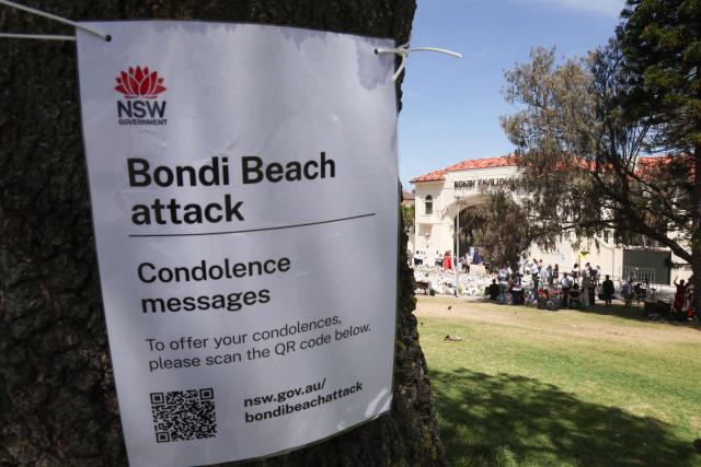 A NSW government sign hung on a tree for people to offer their condolences is seen outside Bondi Pavilion in Sydney on December 18, 2025, to honour victims of the Bondi Beach shooting. The attack at Bondi Beach on December 14 was one of the deadliest in Australian history. (Photo by DAVID GRAY / AFP)