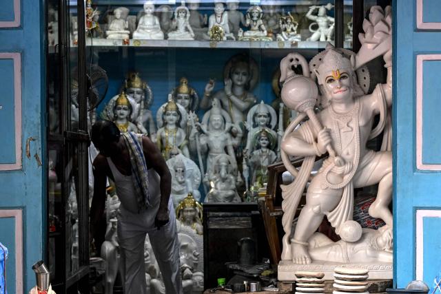 A staff opens a shop selling idols of Hindu deities and saints during early hours in Mumbai on December 18, 2025. (Photo by Indranil MUKHERJEE / AFP)
