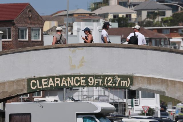 People walk across the footbridge that was used by the father-and-son gunmen during the December 14 Bondi Beach shooting, in Sydney on December 18, 2025. The attack at Bondi Beach on December 14 was one of the deadliest in Australian history. (Photo by DAVID GRAY / AFP)