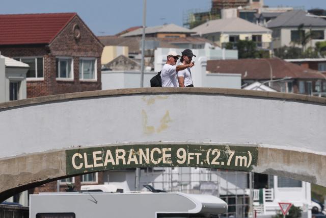 People walk across the footbridge that was used by the father-and-son gunmen during the December 14 Bondi Beach shooting, in Sydney on December 18, 2025. The attack at Bondi Beach on December 14 was one of the deadliest in Australian history. (Photo by DAVID GRAY / AFP)