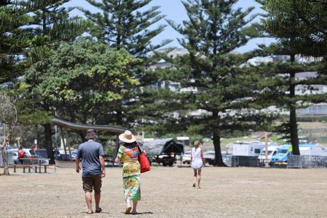 People walk across the crime scene area after it has been reopened to the public following the December 14 Bondi Beach shooting, in Sydney on December 18, 2025. The attack at Bondi Beach on December 14 was one of the deadliest in Australian history. (Photo by DAVID GRAY / AFP)