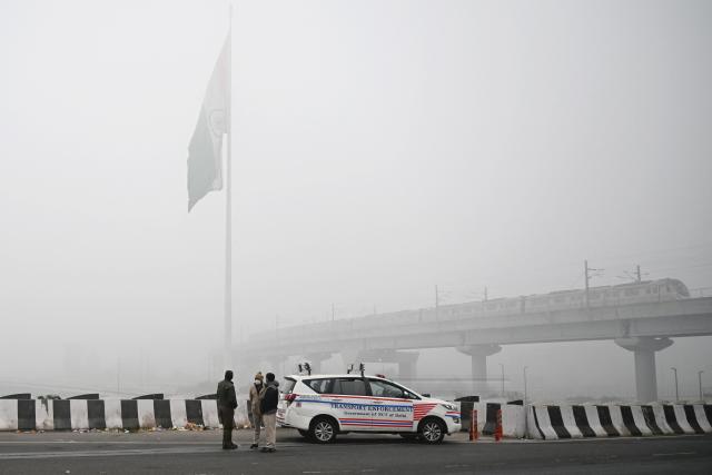 Transport Enforcement personnel stand along a road during vehicle inspections amid heavy smog in New Delhi on December 18, 2025. (Photo by Arun SANKAR / AFP)