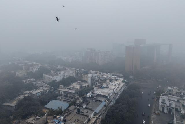 An aerial view shows buildings engulfed in dense smog in New Delhi on December 18, 2025. (Photo by Arun SANKAR / AFP)