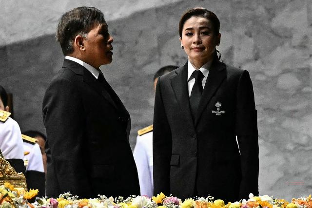 (FILES) Thailand's King Maha Vajiralongkorn (L) and Queen Suthida (R) stand for the royal anthem as they attend the opening ceremony of the 33rd Southeast Asian Games (SEA Games) at Rajamangala National Stadium in Bangkok on December 9, 2025. The queen of Thailand on December 18 won a gold medal in sailing at the Southeast Asian Games, a regional competition being held in her country this month. Queen Suthida, the wife of King Maha Vajiralongkorn, competed in the mixed keelboat SSL47 category, on a 47-foot (14-metre) sailboat with nine other crew members. (Photo by Lillian SUWANRUMPHA / AFP)