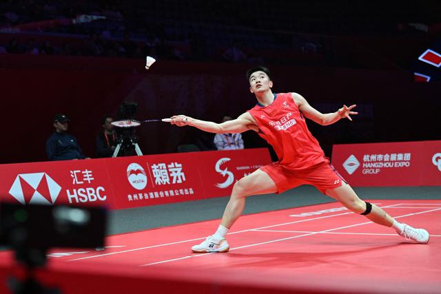 China’s Li Shifeng hits a return to Japan’s Kodai Naraoka during their men's singles match at the BWF Badminton World Tour Finals at the Hangzhou Olympic Sports Centre Gymnasium in Hangzhou, in eastern China's Zhejiang province on December 18, 2025. (Photo by Jade Gao / AFP)