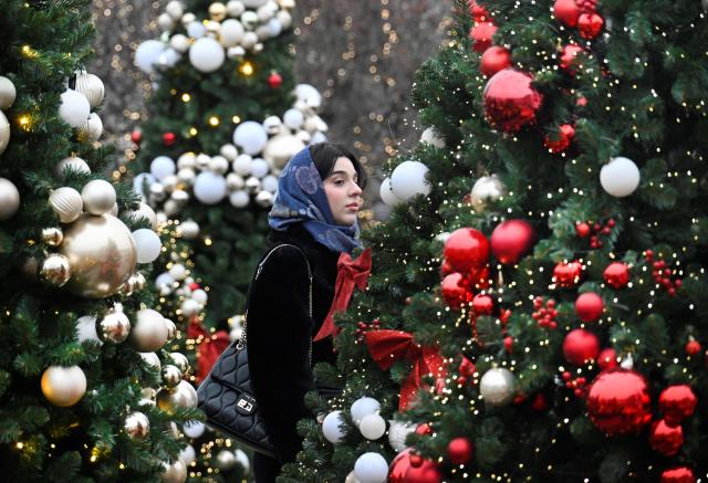 A woman enjoys the Christmas decoration in central Moscow on December 18, 2025, in preparation for the New Year and Christmas holidays. (Photo by Alexander NEMENOV / AFP)