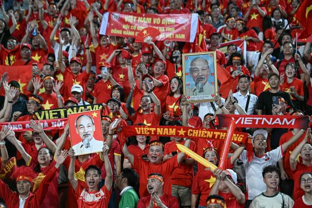 Supporters of Vietnam cheer for their team prior to the men's football final match between Thailand and Vietnam during the 33rd Southeast Asian Games (SEA Games) at Rajamangala National Stadium in Bangkok on December 18, 2025. (Photo by Lillian SUWANRUMPHA / AFP)
