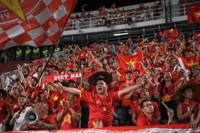 Supporters of Vietnam cheer for their team prior to the men's football final match between Thailand and Vietnam during the 33rd Southeast Asian Games (SEA Games) at Rajamangala National Stadium in Bangkok on December 18, 2025. (Photo by Lillian SUWANRUMPHA / AFP)