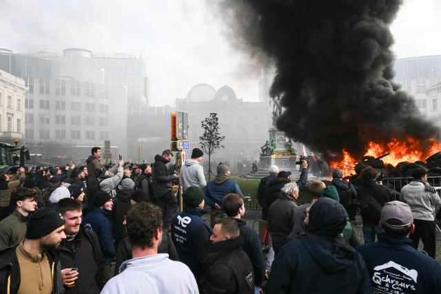 Farmers stand next to tractors and a fire near the European Parliament at the Place du Luxembourg, during a farmers' protest to denounce the reforms of the Common Agricultural Policy (CAP) and trade agreements such as the Mercosur, in Brussels, on December 18, 2025, organised by Copa-Cogeca, the main association representing farmers and agricultural cooperatives in the EU. EU Farmers, particularly in France, worry the Mercosur deal -- which will be discussed at the EU leaders meeting -- will see them undercut by a flow of cheaper goods from agricultural giant Brazil and its neighbours. They also oppose plans put forward by the European Commission to overhaul the 27-nation bloc's huge farming subsidies, fearing less money will flow their way. (Photo by NICOLAS TUCAT / AFP)