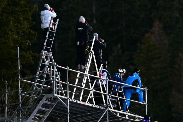 Coaches stand on ladders for a better view of the action during the FIS Alpine Skiing men's World Cup Downhill replacing Beaver Creek in Val Gardena, on December 18, 2025. (Photo by Stefano RELLANDINI / AFP)