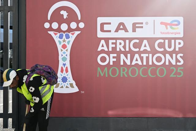 An employee sweeps the area close to the games' logo, as the final touches take place outside of the Al-Medina Stadium in Rabat, on December 18, 2025, ahead of the Africa Cup of Nations (AFCON). The competition begins on December 21. (Photo by Paul ELLIS / AFP)