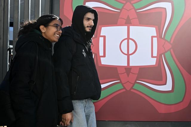 A couple walks past an entrance to the Al-Medina Stadium in Rabat, on December 18, 2025, ahead of the Africa Cup of Nations (AFCON). The competition begins on December 21. (Photo by Paul ELLIS / AFP)