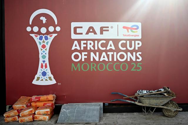 Tools and supplies for workers used to make the final touches to the outside of the Al-Medina Stadium in Rabat, are left near the game's logo on December 18, 2025, ahead of the Africa Cup of Nations (AFCON). The competition begins on December 21. (Photo by Paul ELLIS / AFP)