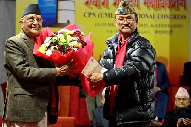 Former Nepali Prime Minister and newly elected leader of the Communist Party of Nepal - Unified Marxist Leninist (CPN-UML), KP Sharma Oli (L) receives flowers during the party's 11th general convention in Kathmandu on December 18, 2025. Members of ousted Nepali prime minister KP Sharma Oli's political party voted for him to retain leadership of the organisation on December 18, meaning he will oversee its preparations for national elections next year. (Photo by PRAKASH MATHEMA / AFP)