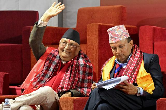Former Nepali Prime Minister and newly elected leader of the Communist Party of Nepal - Unified Marxist Leninist (CPN-UML), KP Sharma Oli (L) waves to supporters during the party's 11th general convention in Kathmandu on December 18, 2025. Members of ousted Nepali prime minister KP Sharma Oli's political party voted for him to retain leadership of the organisation on December 18, meaning he will oversee its preparations for national elections next year. (Photo by PRAKASH MATHEMA / AFP)