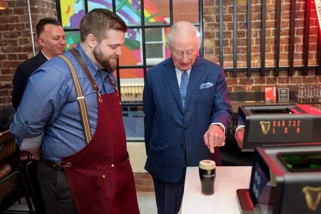 Britain's King Charles III watches as a festive image is printed on a pint of Guinness during his visit to officially open the Guinness Open Gate Brewery London on December 18, 2025. The Guinness Open Gate Brewery, a Ј73 million investment, contains a microbrewery, visitor experience, restaurants, shops, and events space, and will serve as the UK southern hub for Diageo’s award-winning Learning for Life programme. (Photo by Chris Jackson / POOL / AFP)