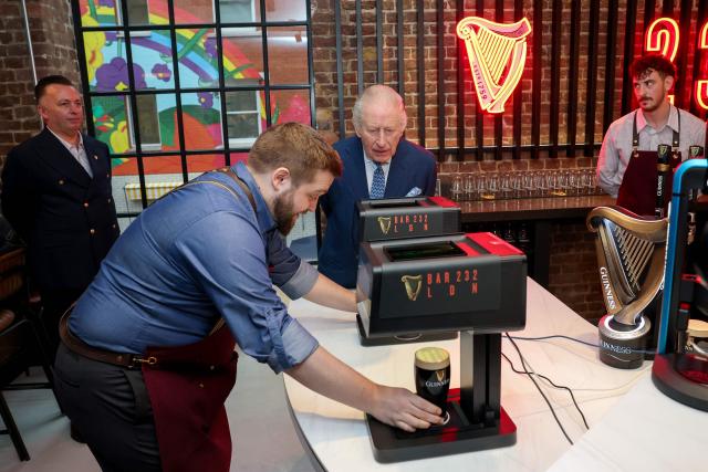 Britain's King Charles III watches as a festive image is printed on a pint of Guinness during his visit to officially open the Guinness Open Gate Brewery London on December 18, 2025. The Guinness Open Gate Brewery, a Ј73 million investment, contains a microbrewery, visitor experience, restaurants, shops, and events space, and will serve as the UK southern hub for Diageo’s award-winning Learning for Life programme. (Photo by Chris Jackson / POOL / AFP)
