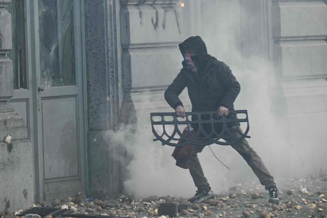 A protestor holds a barrier next to the facade of the European Parliament during a farmers' protest to denounce the reforms of the Common Agricultural Policy (CAP) and trade agreements such as the Mercosur, in Brussels, on December 18, 2025, organised by Copa-Cogeca, the main association representing farmers and agricultural cooperatives in the EU. EU Farmers, particularly in France, worry the Mercosur deal -- which will be discussed at the EU leaders meeting -- will see them undercut by a flow of cheaper goods from agricultural giant Brazil and its neighbours. They also oppose plans put forward by the European Commission to overhaul the 27-nation bloc's huge farming subsidies, fearing less money will flow their way. (Photo by NICOLAS TUCAT / AFP)