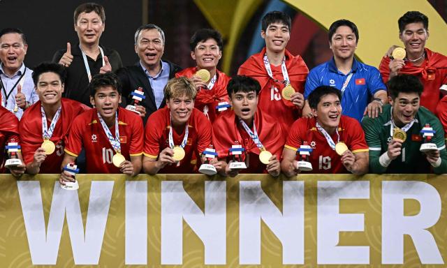 Vietnam's players and staff members pose with their gold medal after winning their men's football final match against Thailand during the 33rd Southeast Asian Games (SEA Games) at Rajamangala National Stadium in Bangkok on December 18, 2025. (Photo by Lillian SUWANRUMPHA / AFP)