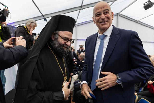 Greece's Minister of National Defence Nikos Dendias speaks with Archbishop of France Dimitrios Ploumis during the delivery ceremony of the Defence and Intervention frigate HS Kimon to the Greek Navy in Lorient, western France on December 18, 2025. (Photo by Fred TANNEAU / AFP)