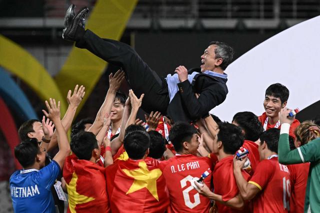 Vietnam's players and staff members celebrate after winning the men's football final match against Thailand during the 33rd Southeast Asian Games (SEA Games) at Rajamangala National Stadium in Bangkok on December 18, 2025. (Photo by Lillian SUWANRUMPHA / AFP)